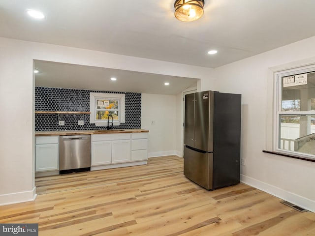 kitchen featuring butcher block countertops, sink, white cabinets, decorative backsplash, and stainless steel appliances