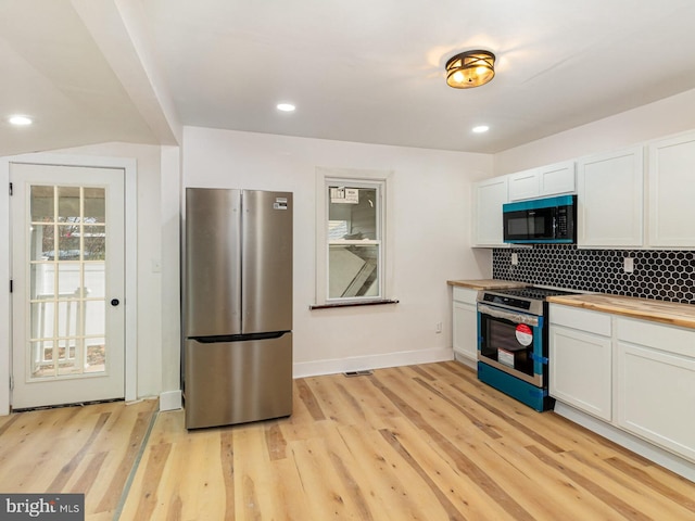 kitchen featuring white cabinetry, appliances with stainless steel finishes, butcher block counters, and light hardwood / wood-style floors