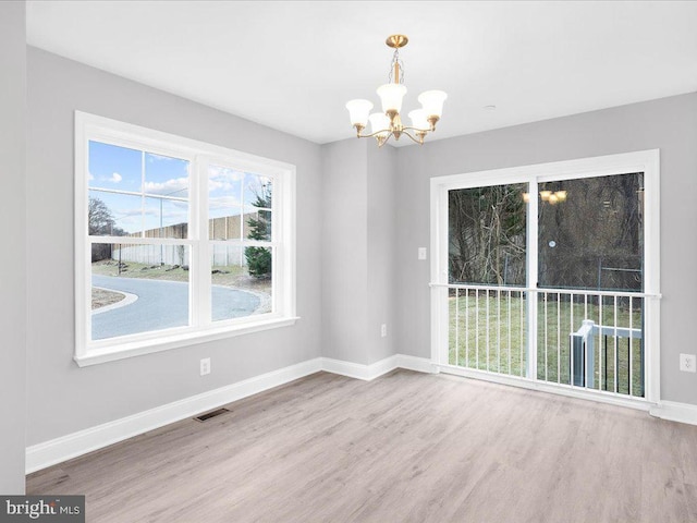 unfurnished dining area with hardwood / wood-style floors and a notable chandelier