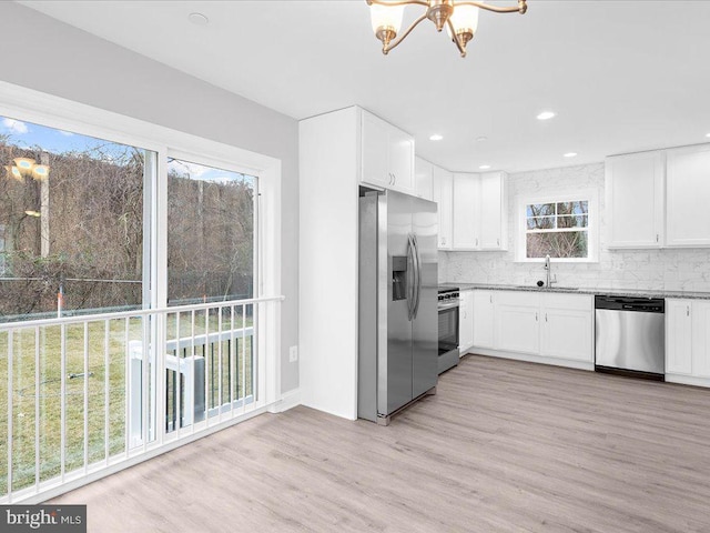 kitchen featuring sink, tasteful backsplash, stainless steel appliances, light hardwood / wood-style floors, and white cabinets