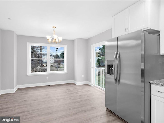 kitchen with white cabinetry, decorative light fixtures, light wood-type flooring, stainless steel fridge, and a notable chandelier