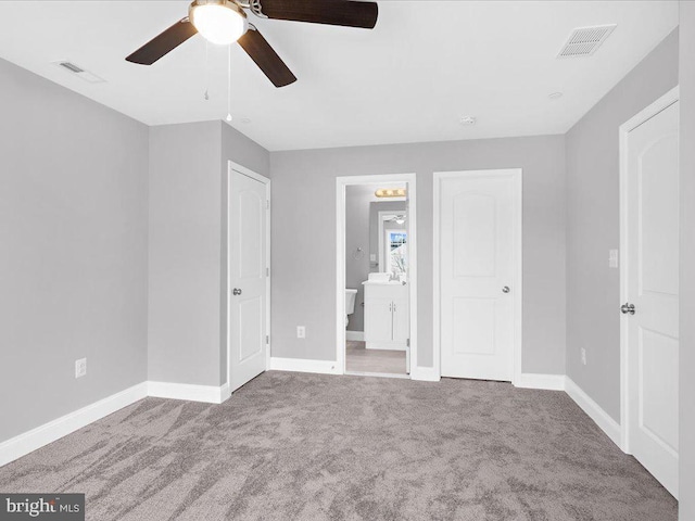 unfurnished bedroom featuring ensuite bath, carpet floors, and ceiling fan