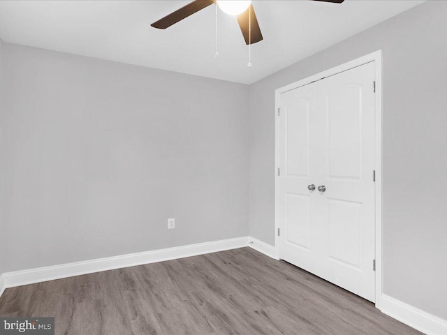 unfurnished bedroom featuring ceiling fan, wood-type flooring, and a closet