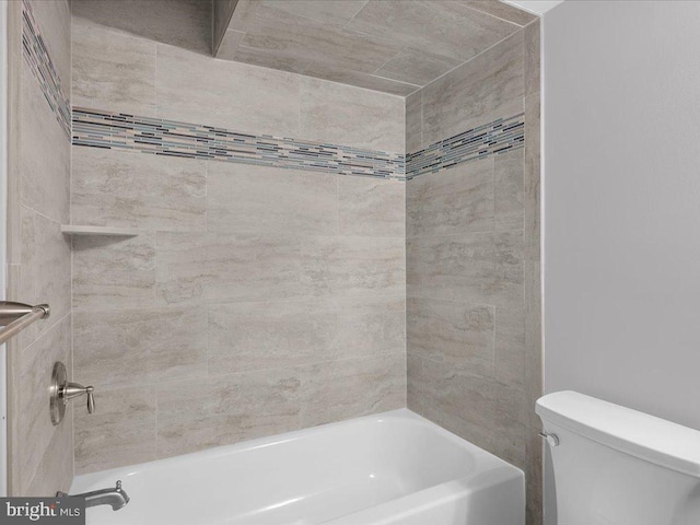 bathroom featuring tiled shower / bath combo and toilet