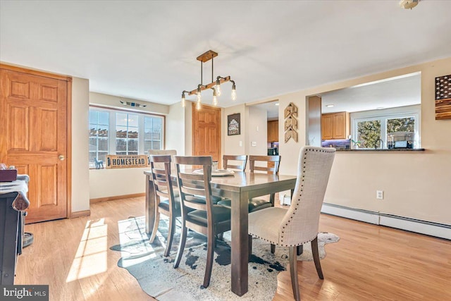 dining area featuring a baseboard heating unit, a wealth of natural light, and light hardwood / wood-style flooring