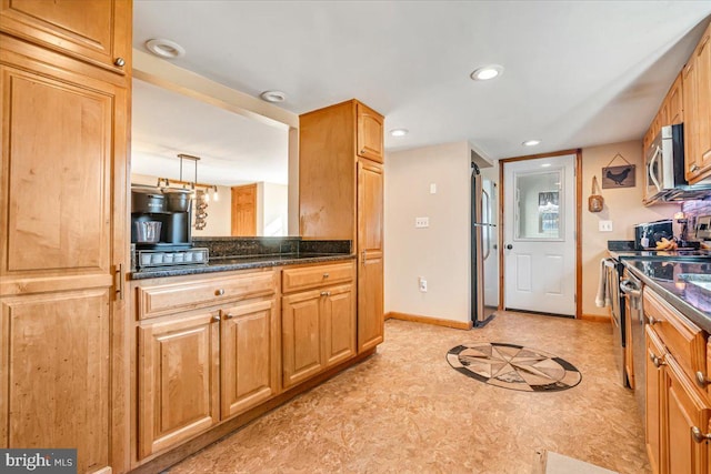 kitchen featuring appliances with stainless steel finishes, dark stone countertops, and decorative light fixtures