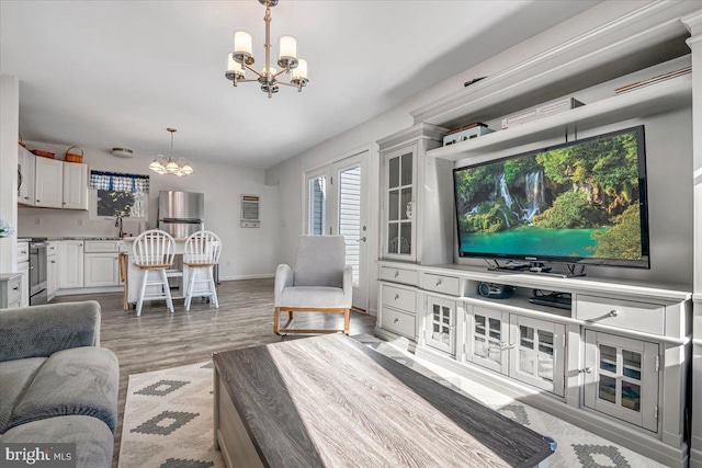 living room featuring a notable chandelier, sink, and light wood-type flooring