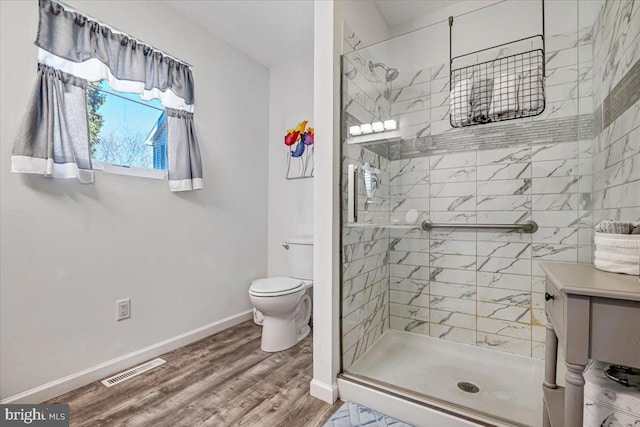 bathroom with a shower with shower door, toilet, and wood-type flooring