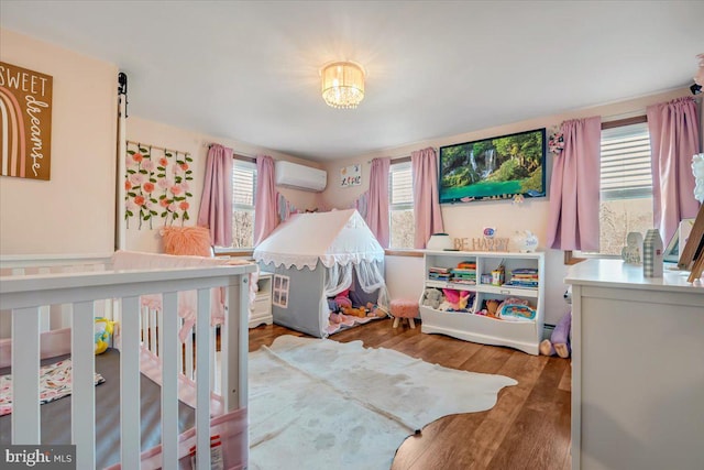 bedroom featuring multiple windows, hardwood / wood-style floors, and a wall unit AC