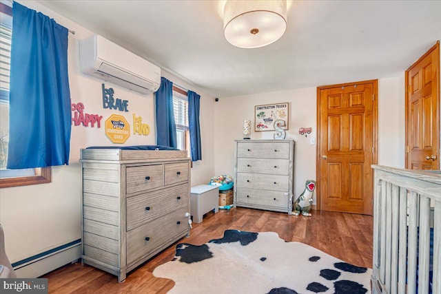 bedroom with hardwood / wood-style flooring, a wall unit AC, and a baseboard heating unit