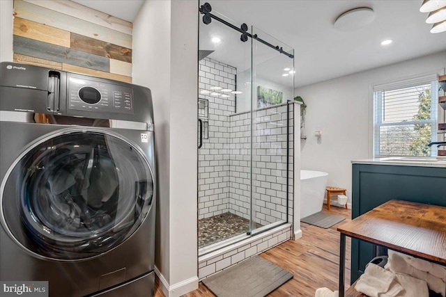 bathroom with washer / clothes dryer, shower with separate bathtub, hardwood / wood-style flooring, and sink