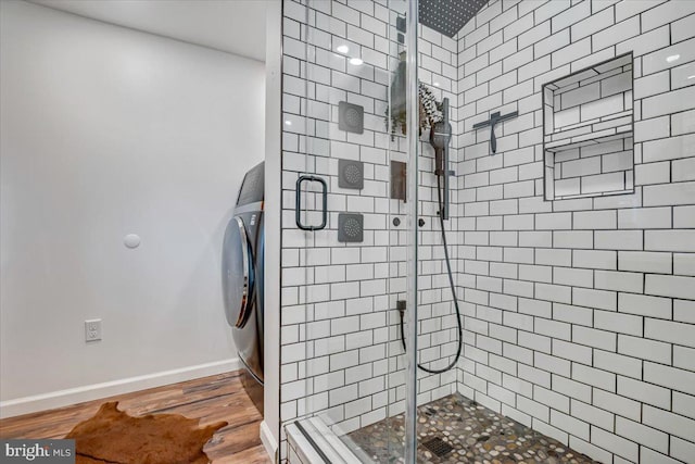 bathroom featuring an enclosed shower, washer / clothes dryer, and hardwood / wood-style floors