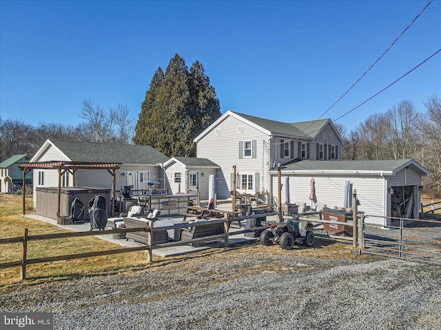 rear view of house with a hot tub and a patio