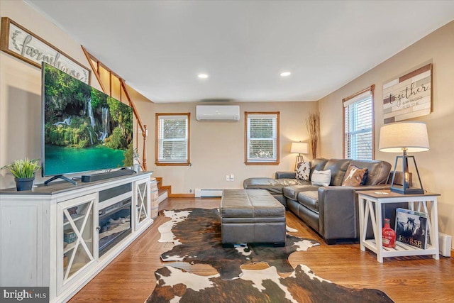 living room featuring wood-type flooring, plenty of natural light, a baseboard heating unit, and a wall mounted air conditioner