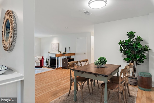 dining area featuring recessed lighting, visible vents, a fireplace, and wood finished floors