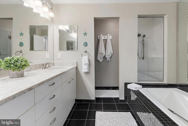 bathroom with a garden tub, a shower stall, vanity, baseboards, and tile patterned floors