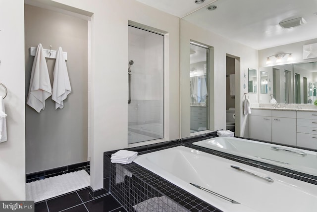 full bath with toilet, vanity, baseboards, a bath, and tile patterned floors