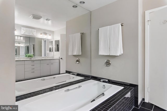 bathroom with double vanity, visible vents, a sink, a bath, and tile patterned floors