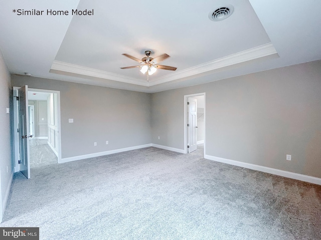 unfurnished room featuring ceiling fan, light colored carpet, ornamental molding, and a tray ceiling