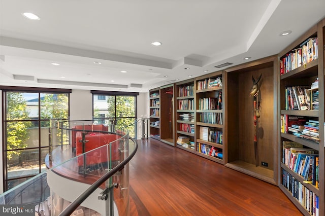 home office featuring hardwood / wood-style flooring, a raised ceiling, and built in shelves