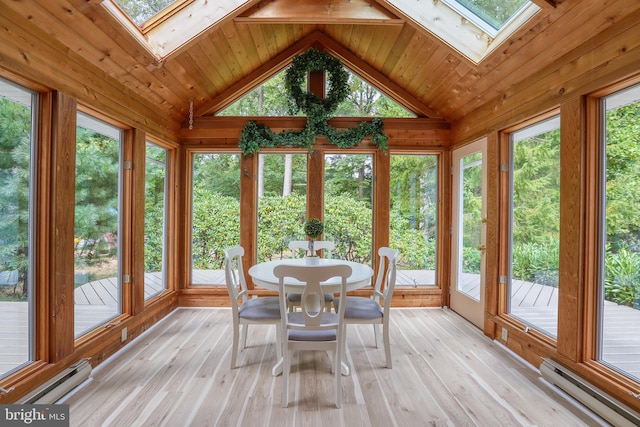 unfurnished sunroom with a baseboard heating unit, vaulted ceiling with skylight, and plenty of natural light