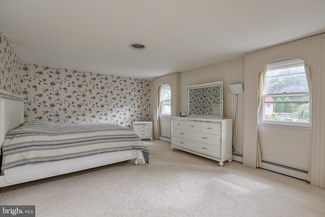 bedroom with a baseboard heating unit and light colored carpet