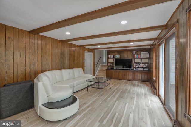 living room with light hardwood / wood-style floors, beamed ceiling, and wooden walls