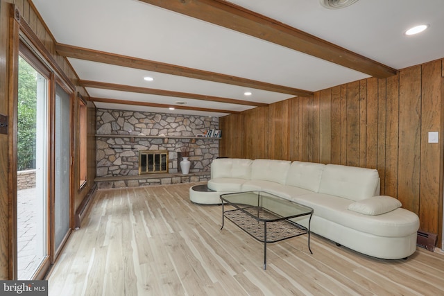 living room with light hardwood / wood-style flooring, beamed ceiling, wood walls, and a fireplace