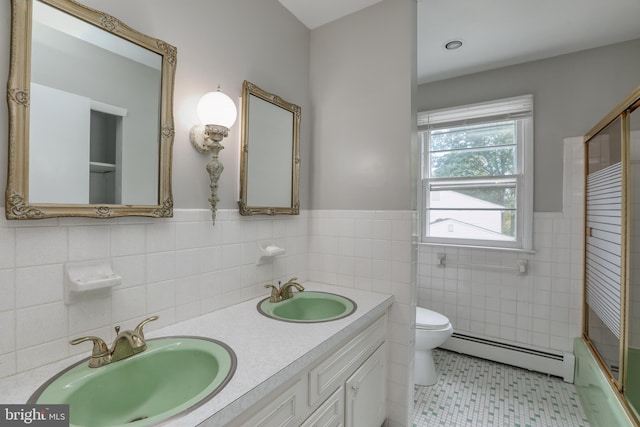 full bathroom featuring tile walls, vanity, a baseboard heating unit, toilet, and enclosed tub / shower combo