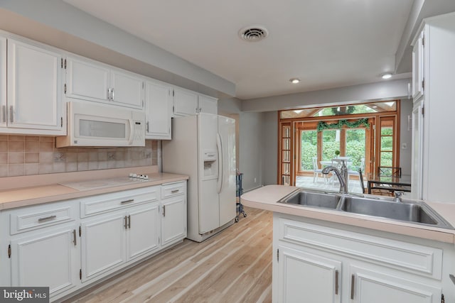 kitchen with light hardwood / wood-style flooring, sink, backsplash, white appliances, and white cabinets