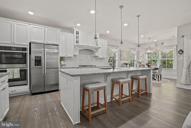 kitchen with sink, white cabinetry, decorative light fixtures, a center island with sink, and appliances with stainless steel finishes