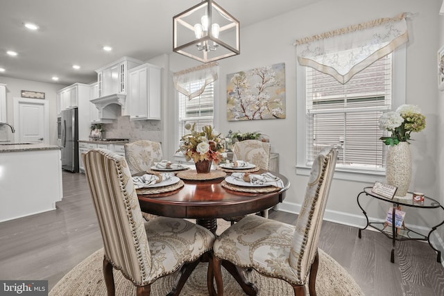 dining area with an inviting chandelier, sink, and dark wood-type flooring