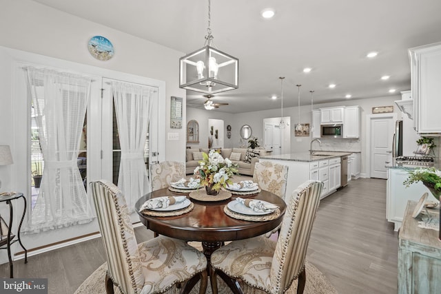 dining area with ceiling fan with notable chandelier, dark wood-type flooring, and sink