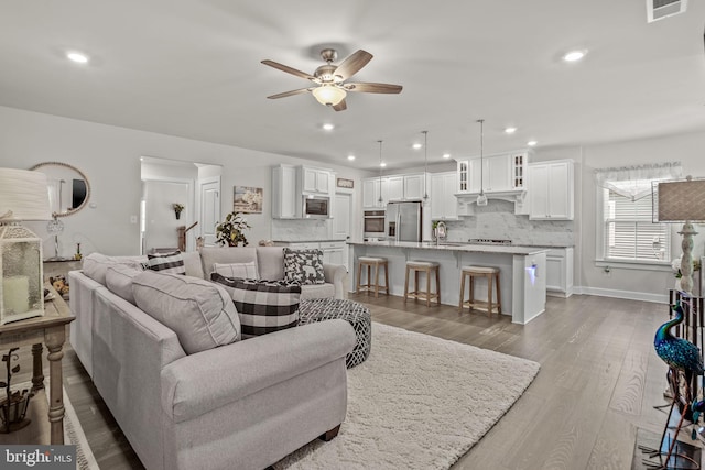 living room featuring sink, ceiling fan, and light wood-type flooring