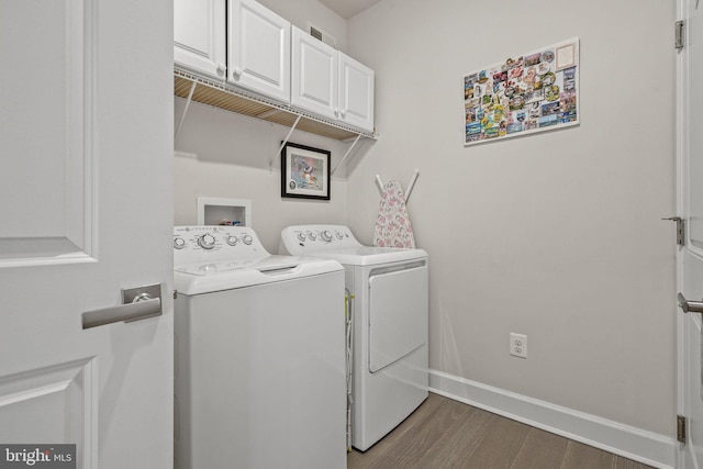 laundry room with cabinets, washer and dryer, and dark wood-type flooring