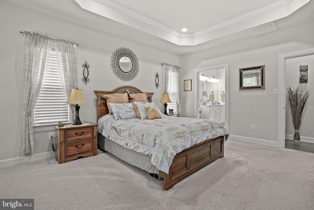 carpeted bedroom with ornamental molding, connected bathroom, and a raised ceiling