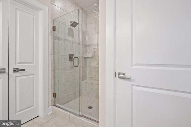 bathroom with tile patterned floors and a shower with door