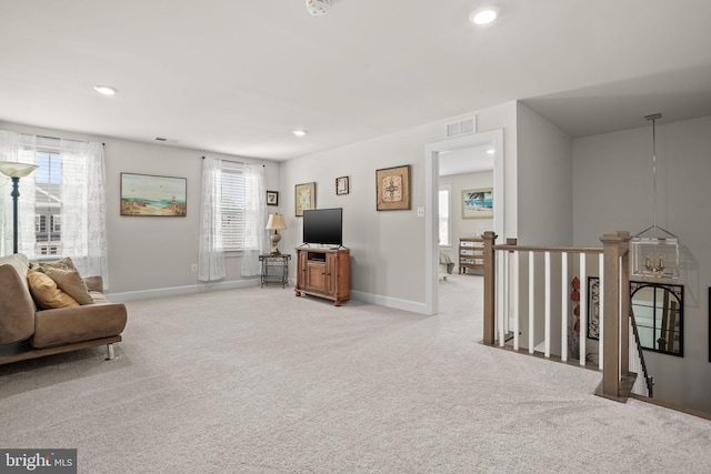 living area featuring light carpet and a healthy amount of sunlight