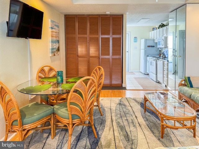 dining space with a textured ceiling and light hardwood / wood-style flooring