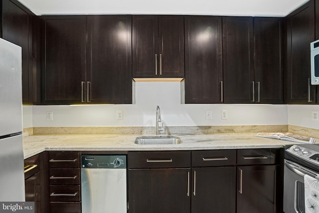 kitchen with light stone counters, dark brown cabinetry, stainless steel appliances, and sink