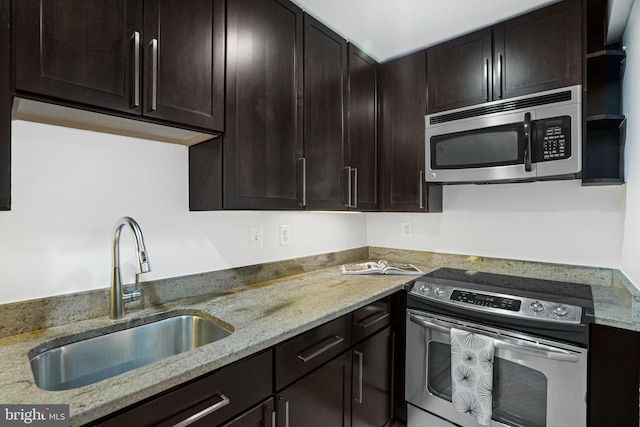 kitchen featuring light stone counters, stainless steel appliances, sink, and dark brown cabinets