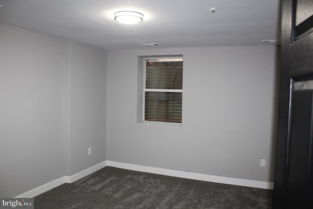 spare room with dark colored carpet