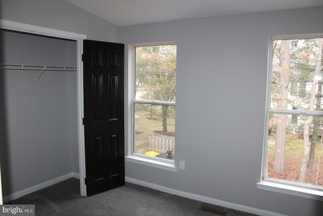 unfurnished bedroom featuring vaulted ceiling, a closet, and dark colored carpet