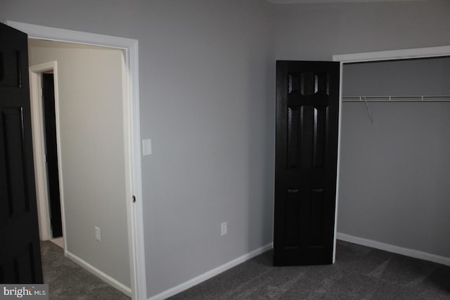 unfurnished bedroom featuring dark colored carpet and a closet