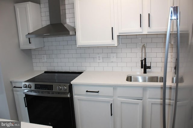 kitchen featuring wall chimney exhaust hood, sink, white cabinetry, stainless steel electric stove, and backsplash