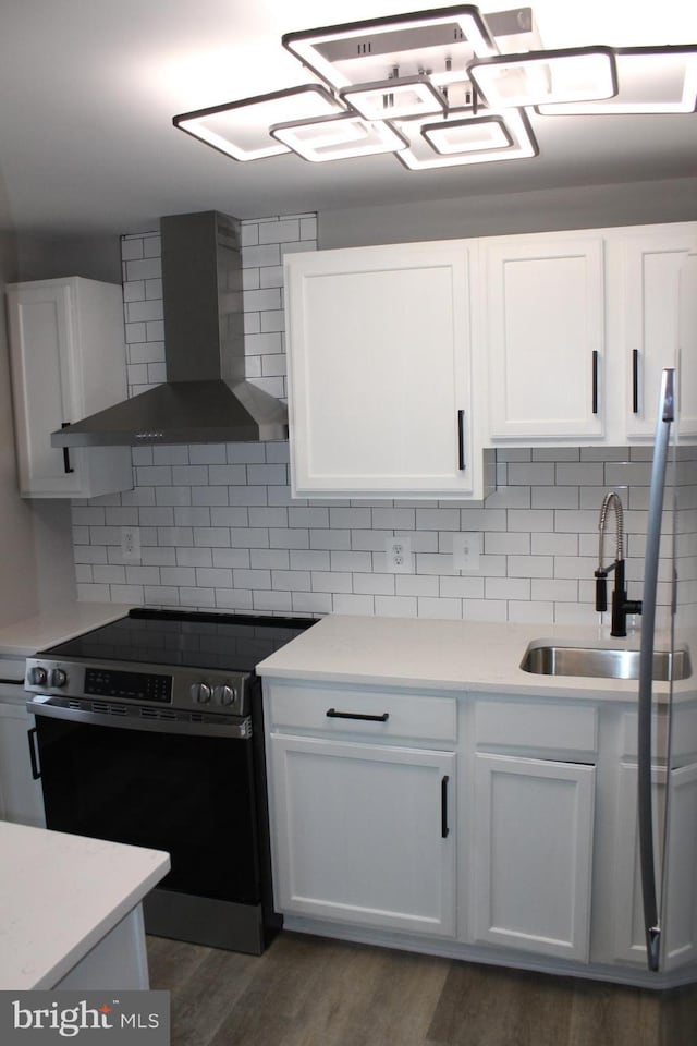 kitchen with wall chimney range hood, sink, white cabinets, and stainless steel electric range oven