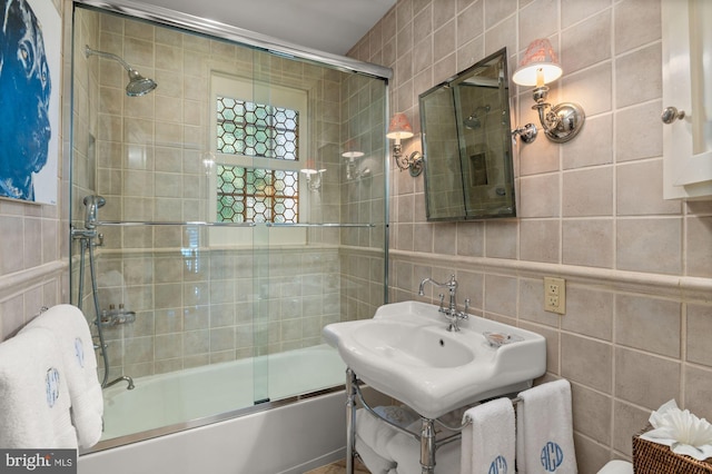 bathroom featuring bath / shower combo with glass door and tile walls