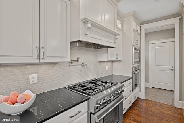 kitchen with decorative backsplash, stainless steel appliances, dark hardwood / wood-style floors, and white cabinets