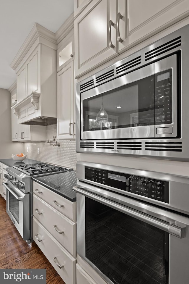 kitchen with stainless steel appliances, white cabinetry, tasteful backsplash, and dark hardwood / wood-style floors