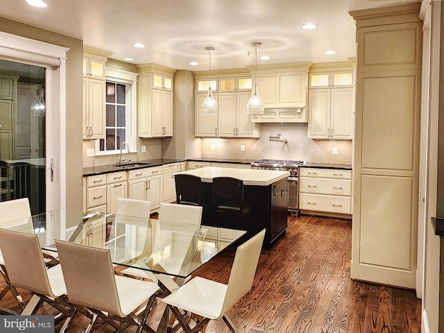 kitchen with dark wood-type flooring, sink, decorative light fixtures, a center island, and high end stove